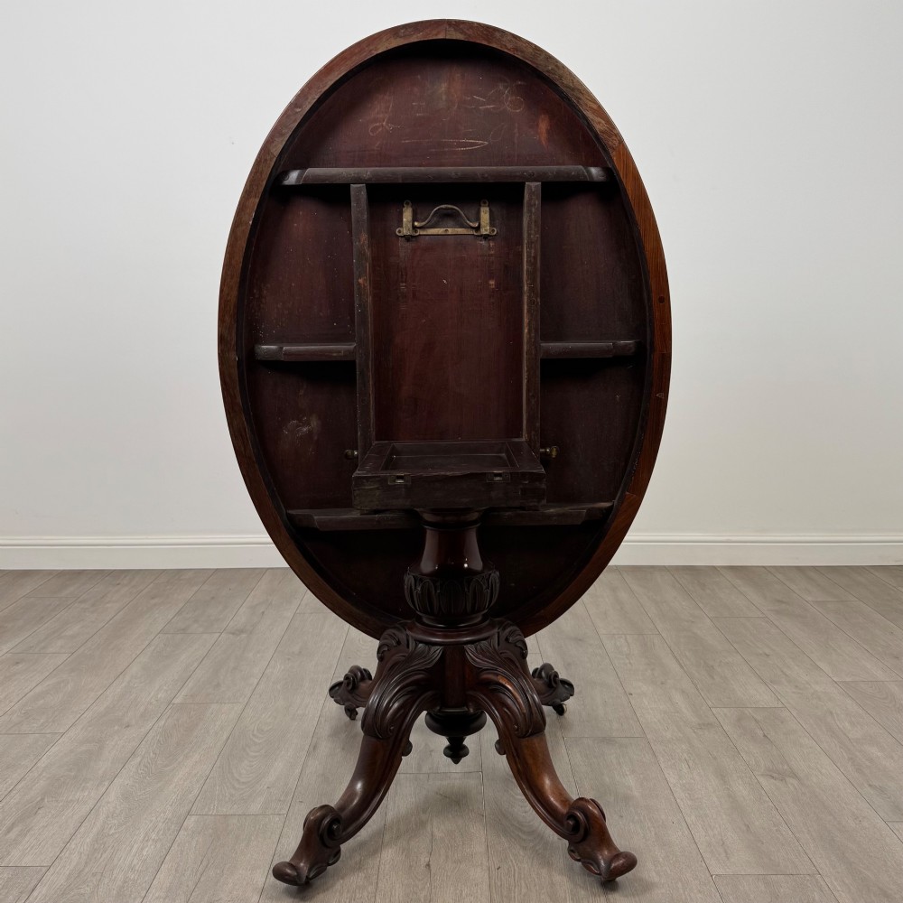 A 19th-century Victorian circular rosewood breakfast table with a carved central pedestal column and four scroll legs with brass castors. View IV
