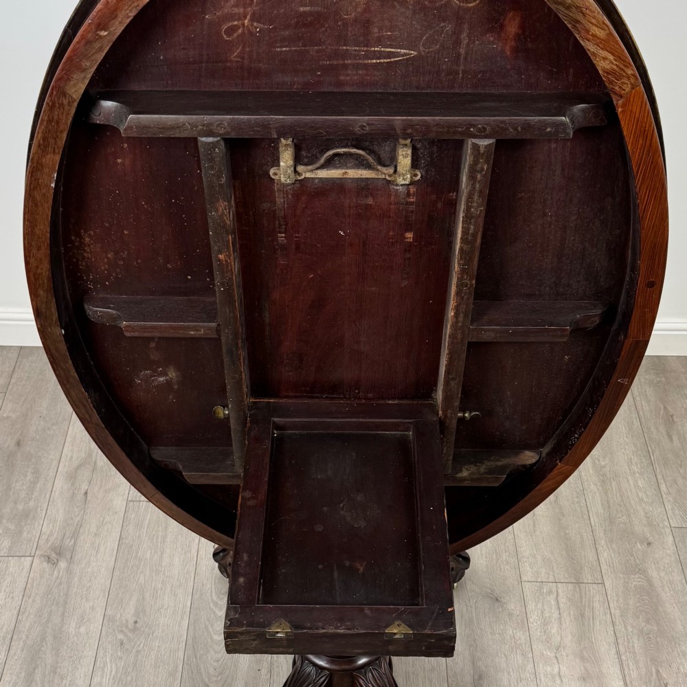A 19th-century Victorian circular rosewood breakfast table with a carved central pedestal column and four scroll legs with brass castors. View VI