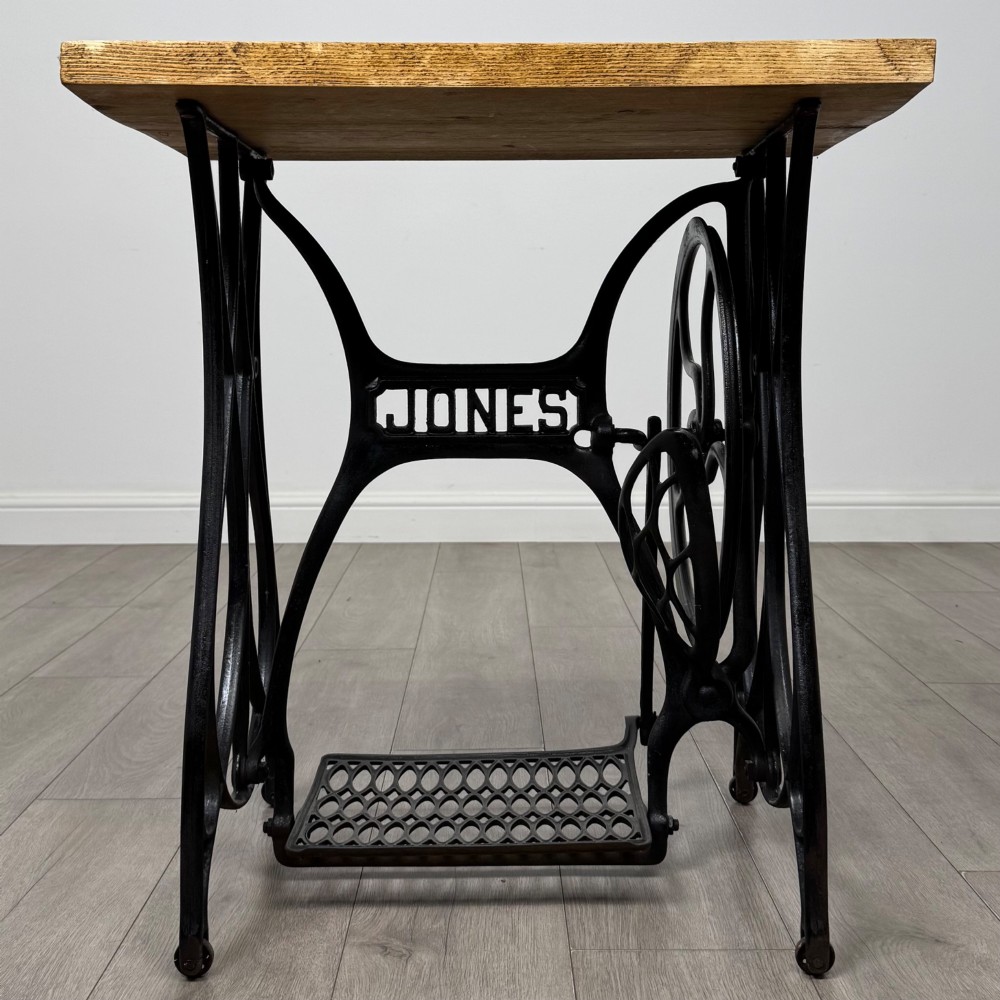 An industrial side table featuring a black cast iron Jones treadle sewing machine base topped with a thick rectangular timber board. View VIII