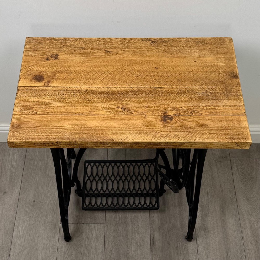 An industrial side table featuring a black cast iron Jones treadle sewing machine base topped with a thick rectangular timber board. View IX
