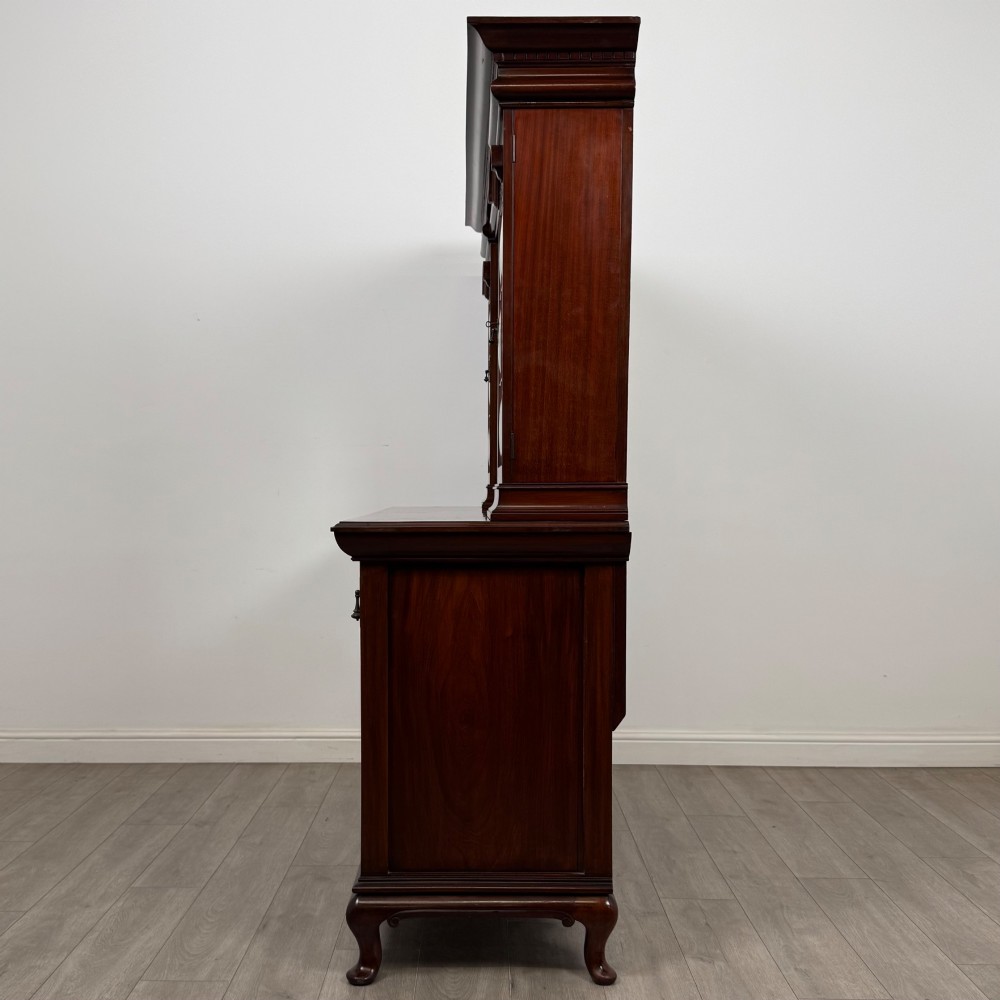 An Arts and Crafts dark mahogany sideboard featuring an upper mirrored superstructure flanked by leaded glass cabinet doors above lower drawers and carved cupboards. View IV