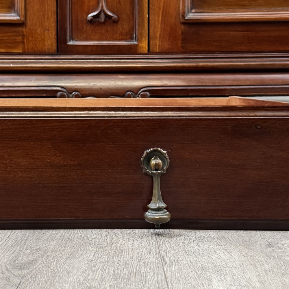 An Arts and Crafts dark mahogany sideboard featuring an upper mirrored superstructure flanked by leaded glass cabinet doors above lower drawers and carved cupboards. View XII