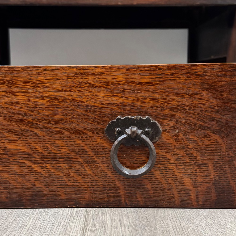 A dark oak Gothic Revival sideboard featuring three central drawers with metal drop ring handles, flanked by two carved tracery panel doors with decorative iron latches. View XII