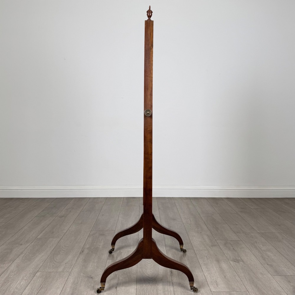 An Edwardian mahogany full-length cheval mirror featuring a rectangular tilting glass frame supported by a wooden upright stand with finials and splayed feet on brass castors. View II