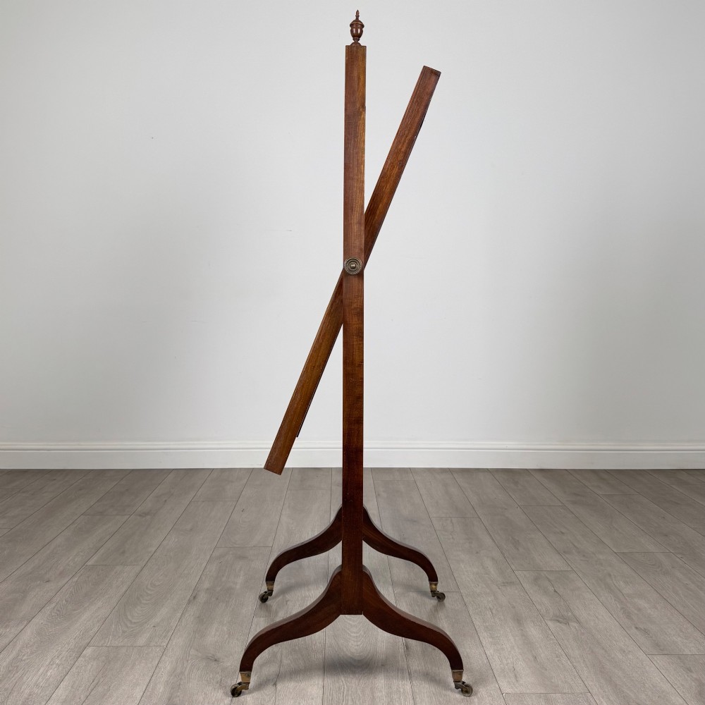An Edwardian mahogany full-length cheval mirror featuring a rectangular tilting glass frame supported by a wooden upright stand with finials and splayed feet on brass castors. View III