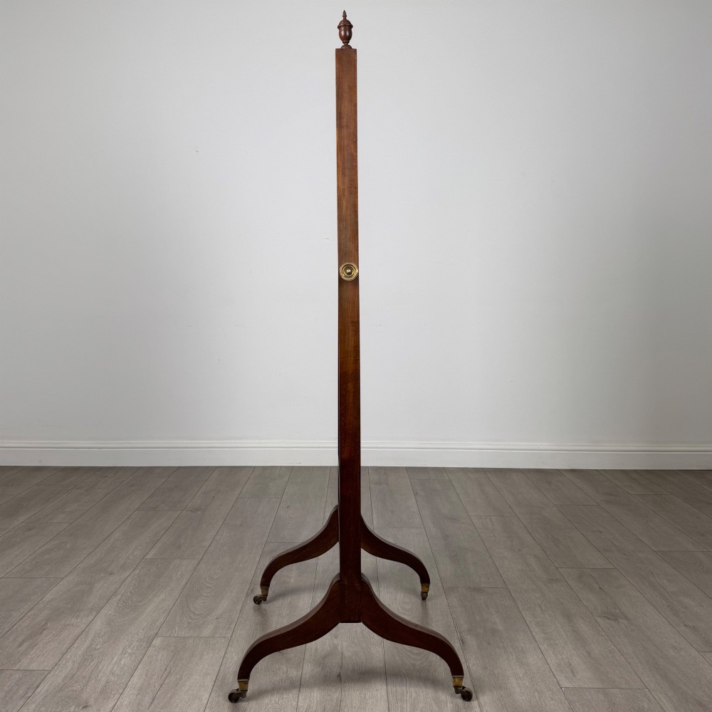 An Edwardian mahogany full-length cheval mirror featuring a rectangular tilting glass frame supported by a wooden upright stand with finials and splayed feet on brass castors. View VII