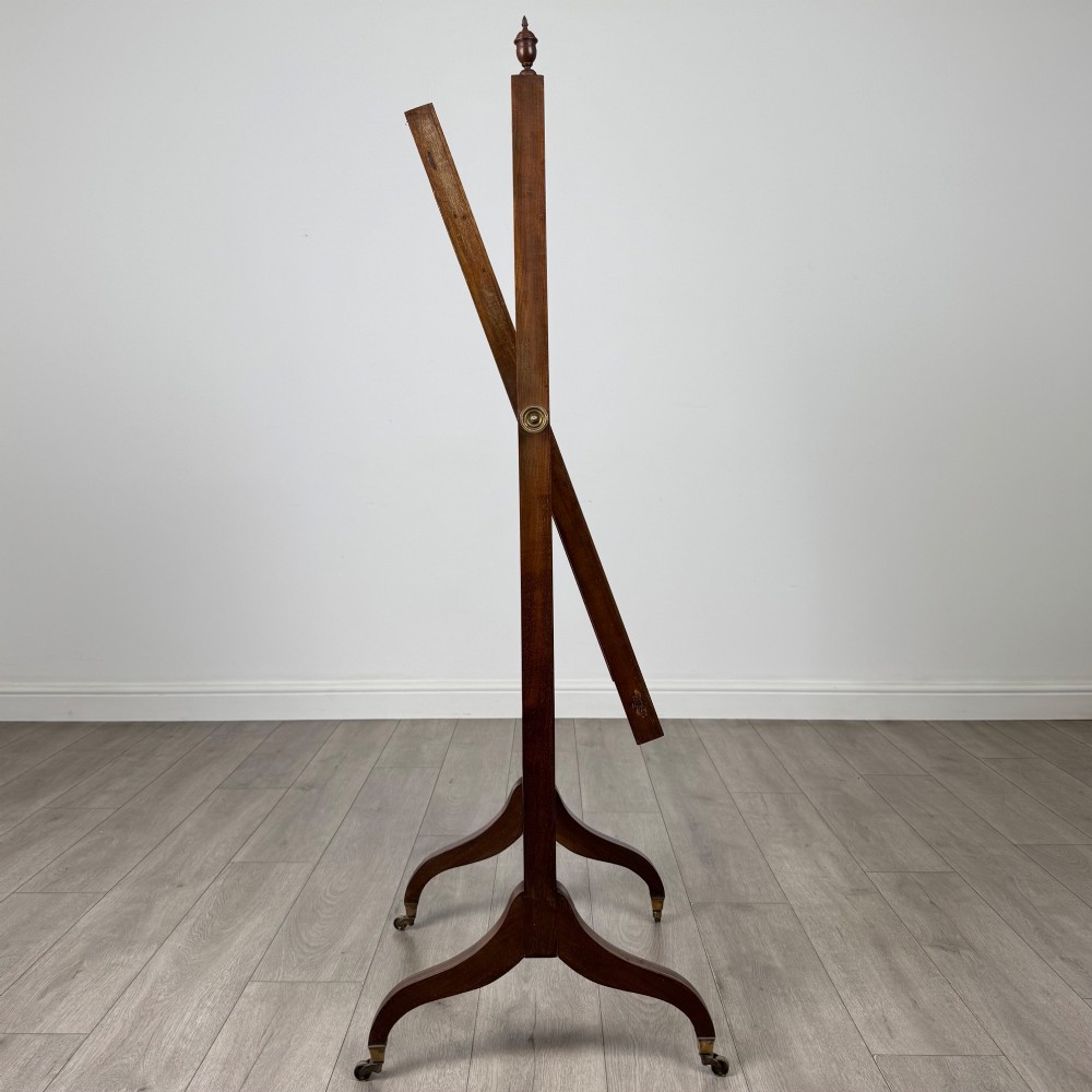 An Edwardian mahogany full-length cheval mirror featuring a rectangular tilting glass frame supported by a wooden upright stand with finials and splayed feet on brass castors. View VIII