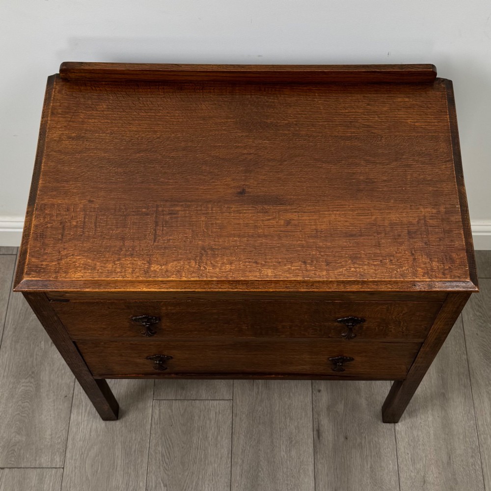 A two-drawer golden oak chest of drawers featuring decorative metal drop handles and straight square legs. View IX