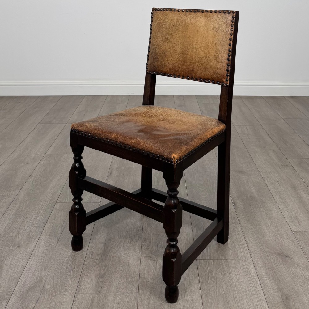 A set of six Edwardian dark oak dining chairs with tan studded leather upholstery, comprising two carver armchairs and four side chairs featuring turned legs. View III