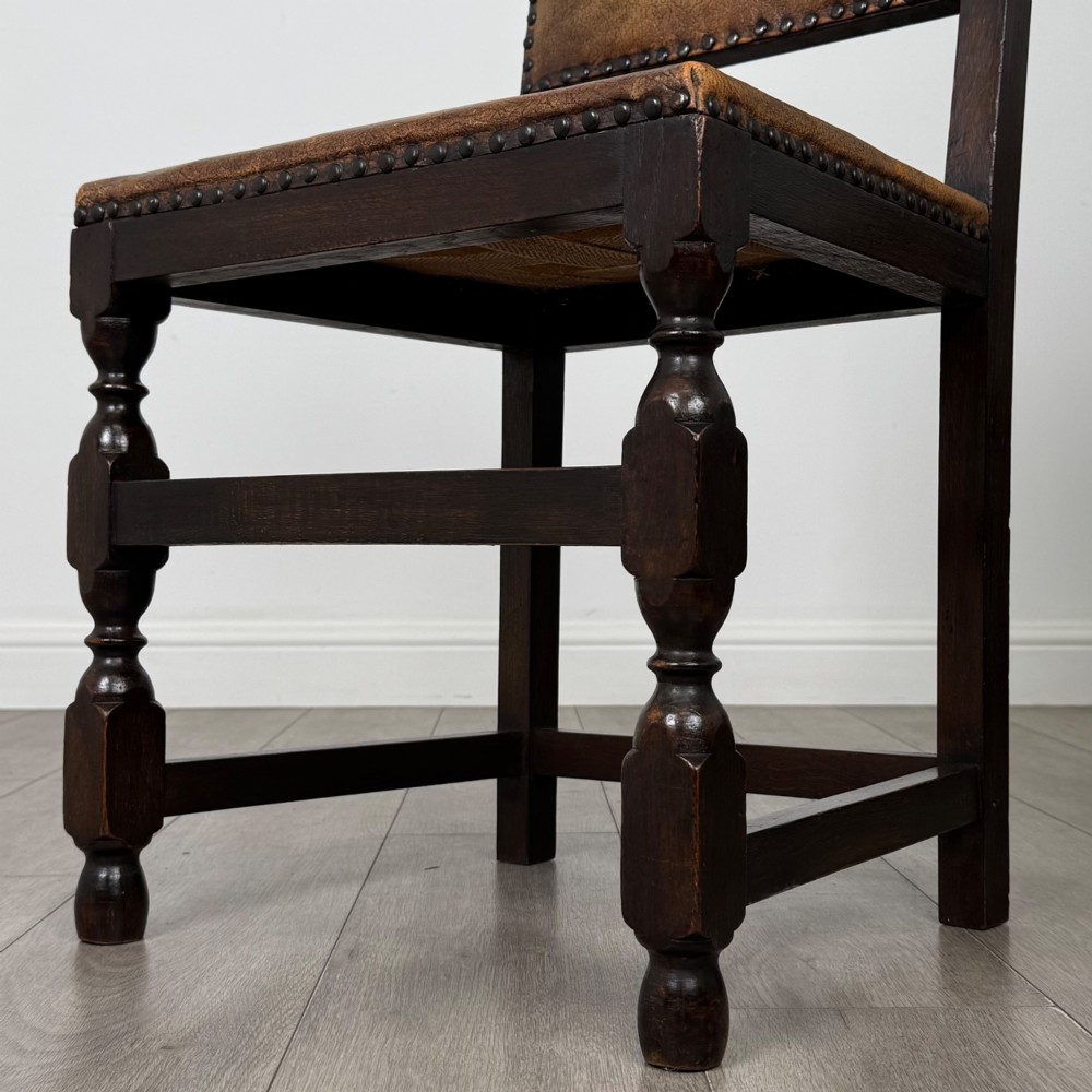 A set of six Edwardian dark oak dining chairs with tan studded leather upholstery, comprising two carver armchairs and four side chairs featuring turned legs. View VII
