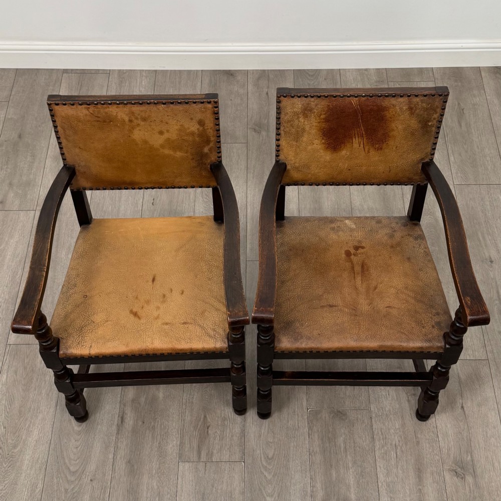A set of six Edwardian dark oak dining chairs with tan studded leather upholstery, comprising two carver armchairs and four side chairs featuring turned legs. View IX