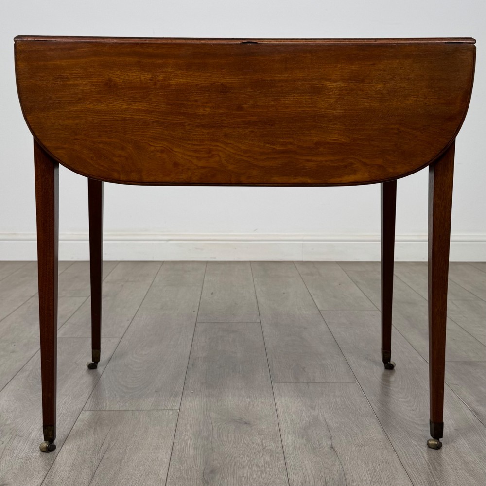 A 19th-century Georgian mahogany Pembroke table featuring two hinged drop-leaf sides, a single drawer with wooden knobs, and square tapered legs on brass castors. View VII