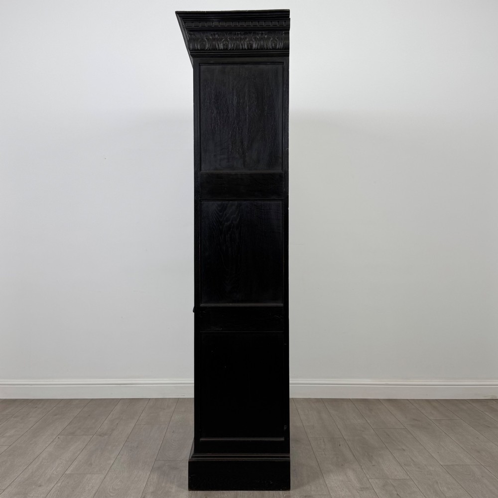 A single-door dark oak Victorian wardrobe featuring geometric panel mouldings, a carved relief face in a central diamond, and a pronounced decorative cornice. View IV