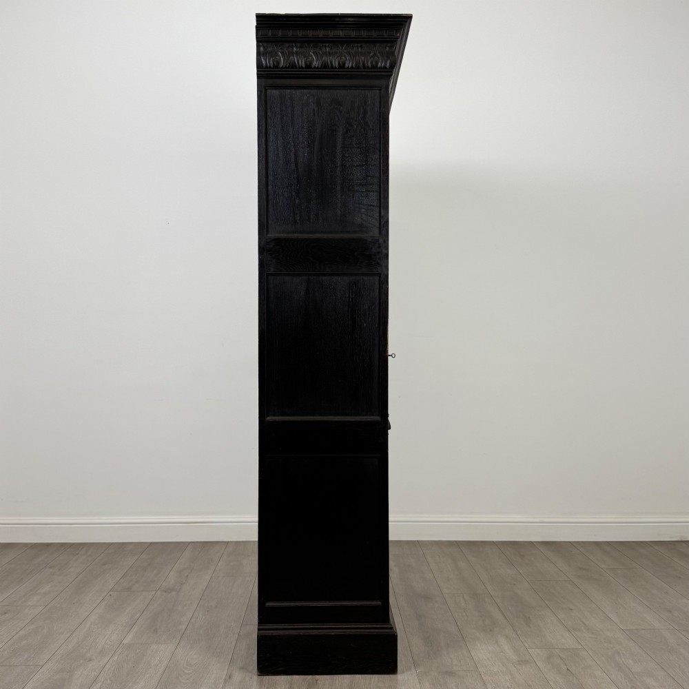 A single-door dark oak Victorian wardrobe featuring geometric panel mouldings, a carved relief face in a central diamond, and a pronounced decorative cornice. View VIII