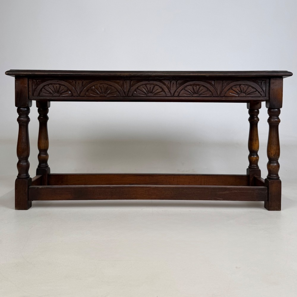 A dark carved oak bench featuring turned legs, a lower box stretcher, and a carved lunette frieze along the apron. View V