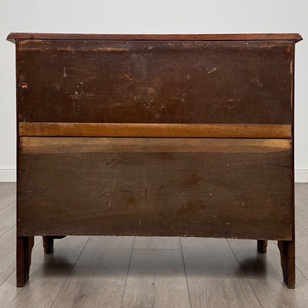 An Edwardian warm brown oak chest of drawers featuring two short upper drawers and two long lower drawers with brass drop handles. View V