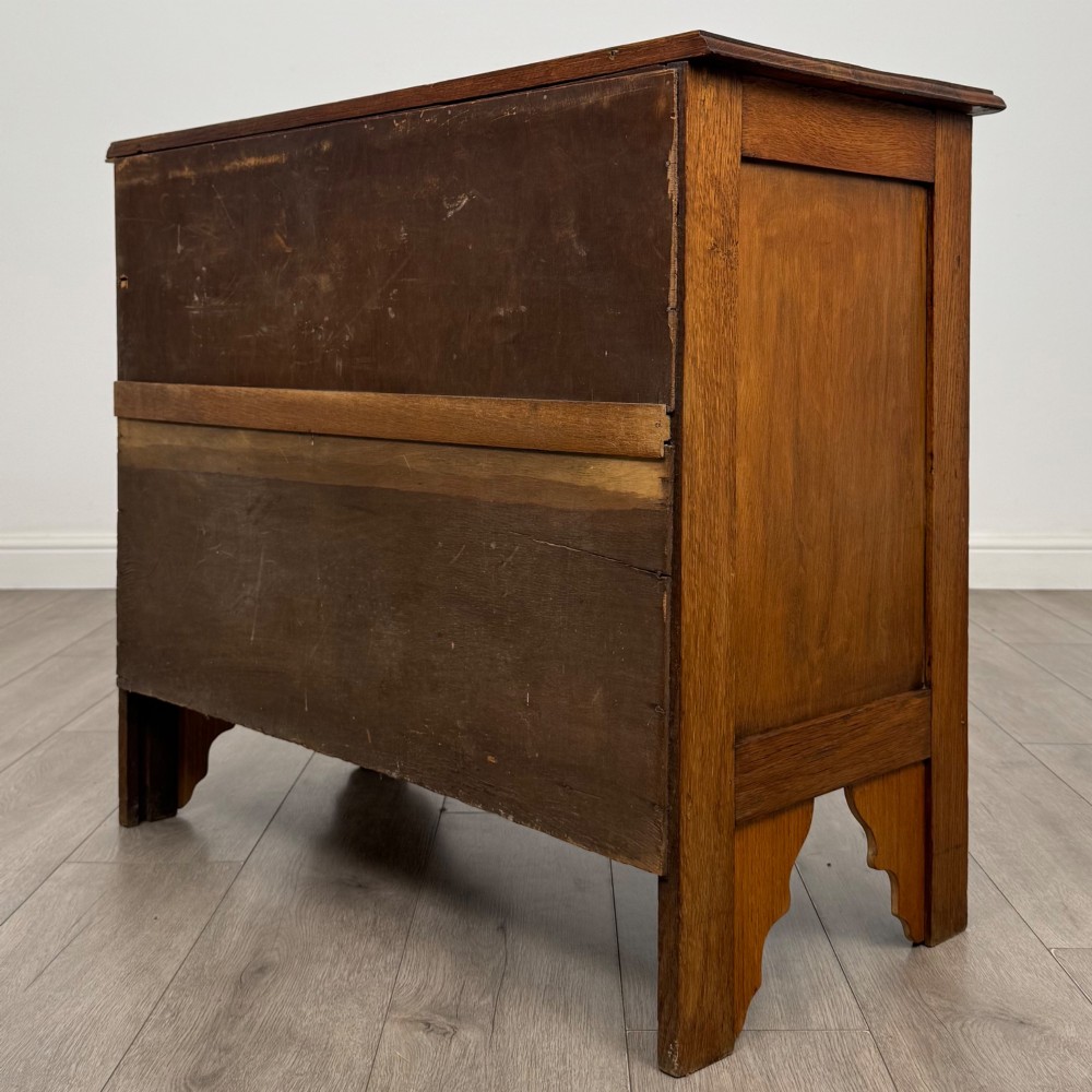 An Edwardian warm brown oak chest of drawers featuring two short upper drawers and two long lower drawers with brass drop handles. View VI