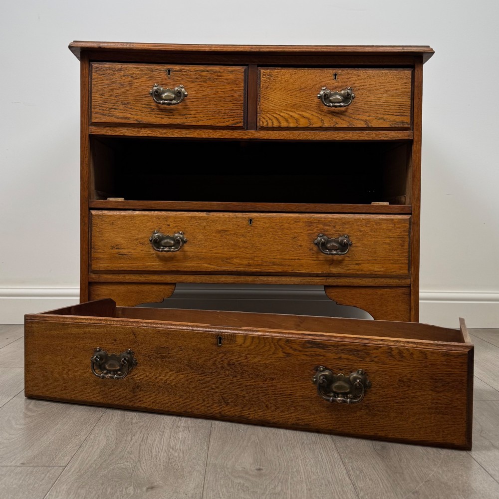 An Edwardian warm brown oak chest of drawers featuring two short upper drawers and two long lower drawers with brass drop handles. View X