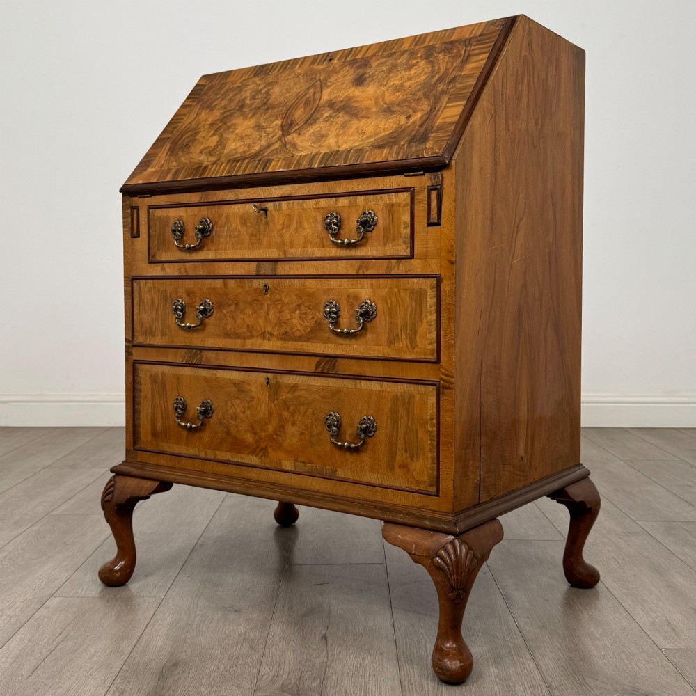 An Edwardian burr walnut writing bureau featuring a sloping fall front, three drawers with decorative brass handles, and cabriole legs. View III