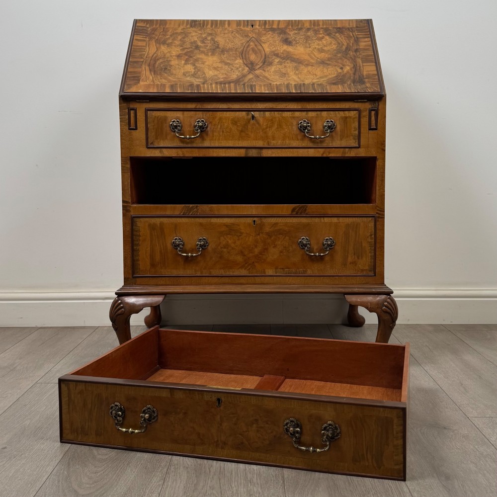 An Edwardian burr walnut writing bureau featuring a sloping fall front, three drawers with decorative brass handles, and cabriole legs. View XII