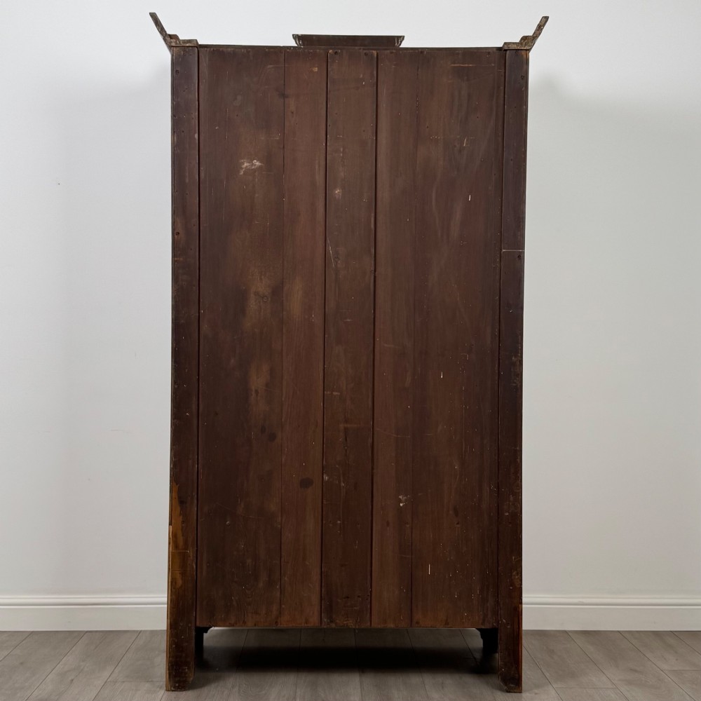An Edwardian walnut wardrobe featuring a central mirrored door flanked by carved timber panels above a single base drawer. View VI