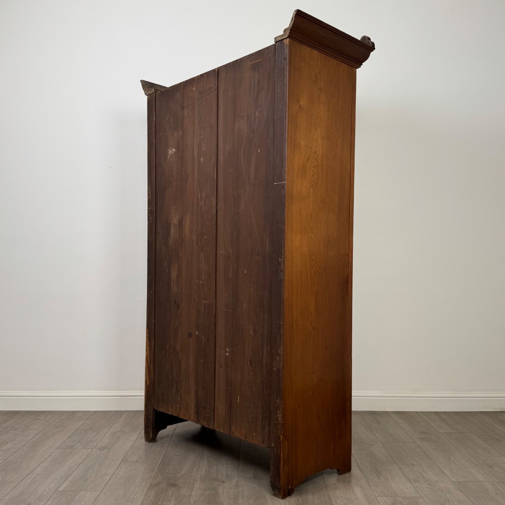 An Edwardian walnut wardrobe featuring a central mirrored door flanked by carved timber panels above a single base drawer. View VII