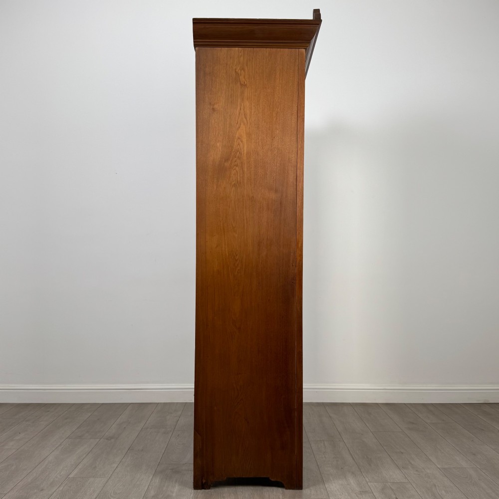 An Edwardian walnut wardrobe featuring a central mirrored door flanked by carved timber panels above a single base drawer. View VIII