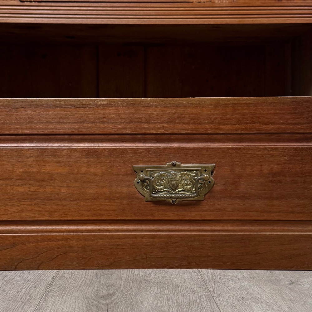 An Edwardian walnut wardrobe featuring a central mirrored door flanked by carved timber panels above a single base drawer. View XI