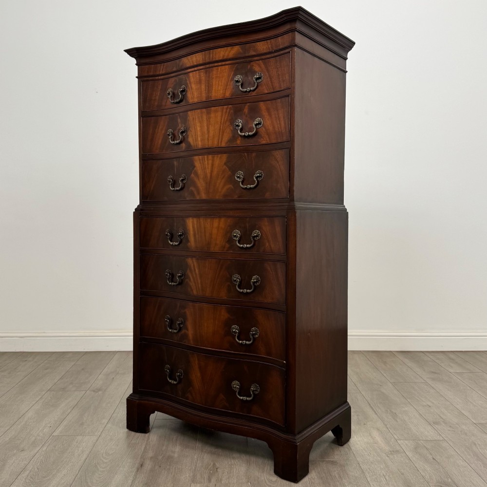 A tall 20th-century mahogany serpentine chest of drawers featuring seven graduated drawers with brass handles and bracket feet. View II