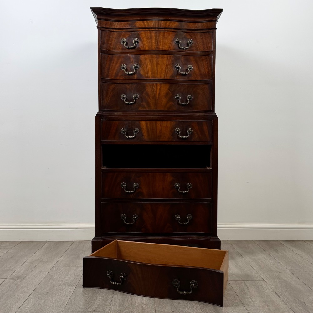A tall 20th-century mahogany serpentine chest of drawers featuring seven graduated drawers with brass handles and bracket feet. View X