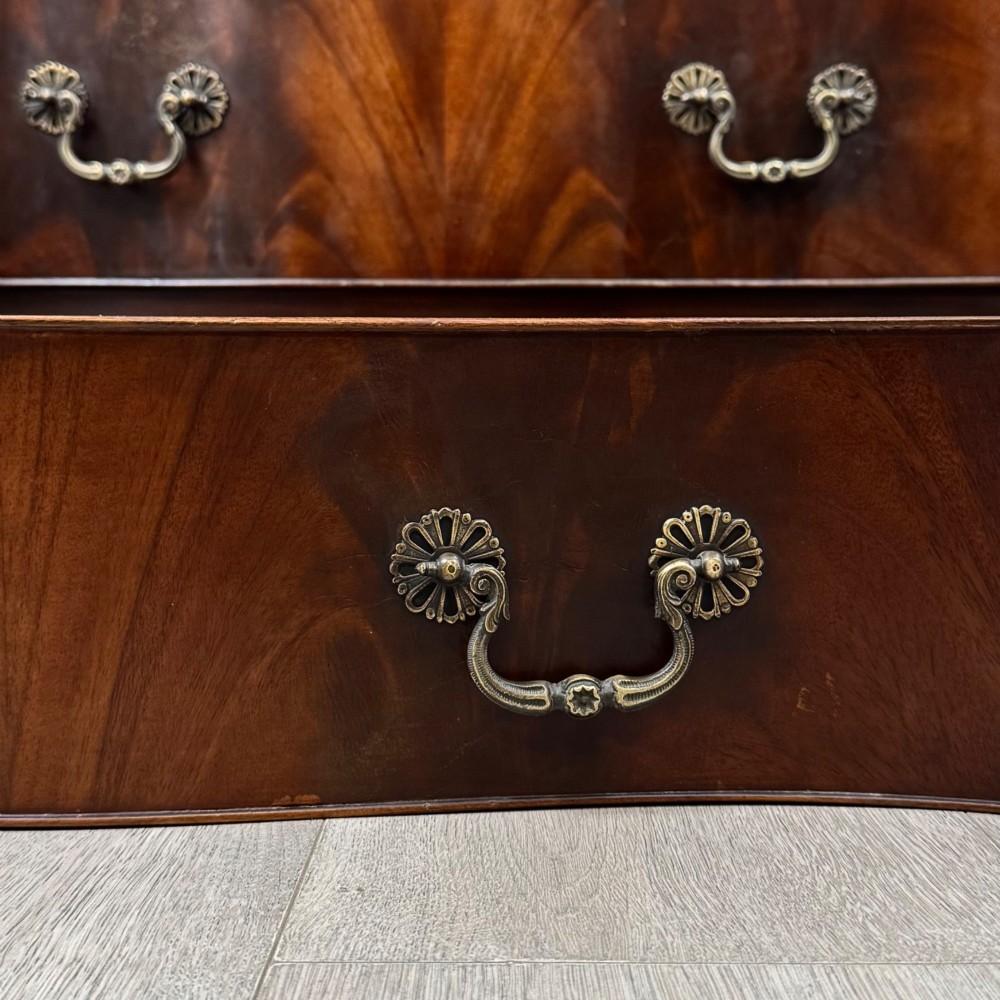 A tall 20th-century mahogany serpentine chest of drawers featuring seven graduated drawers with brass handles and bracket feet. View XI