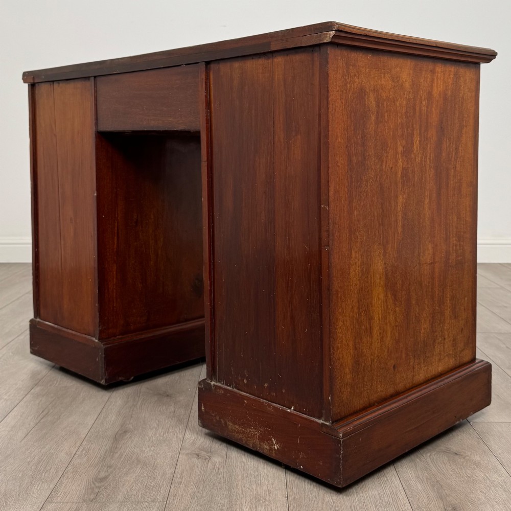 An Edwardian mahogany pedestal desk featuring nine reeded drawers with decorative brass drop handles and a central kneehole. View VI