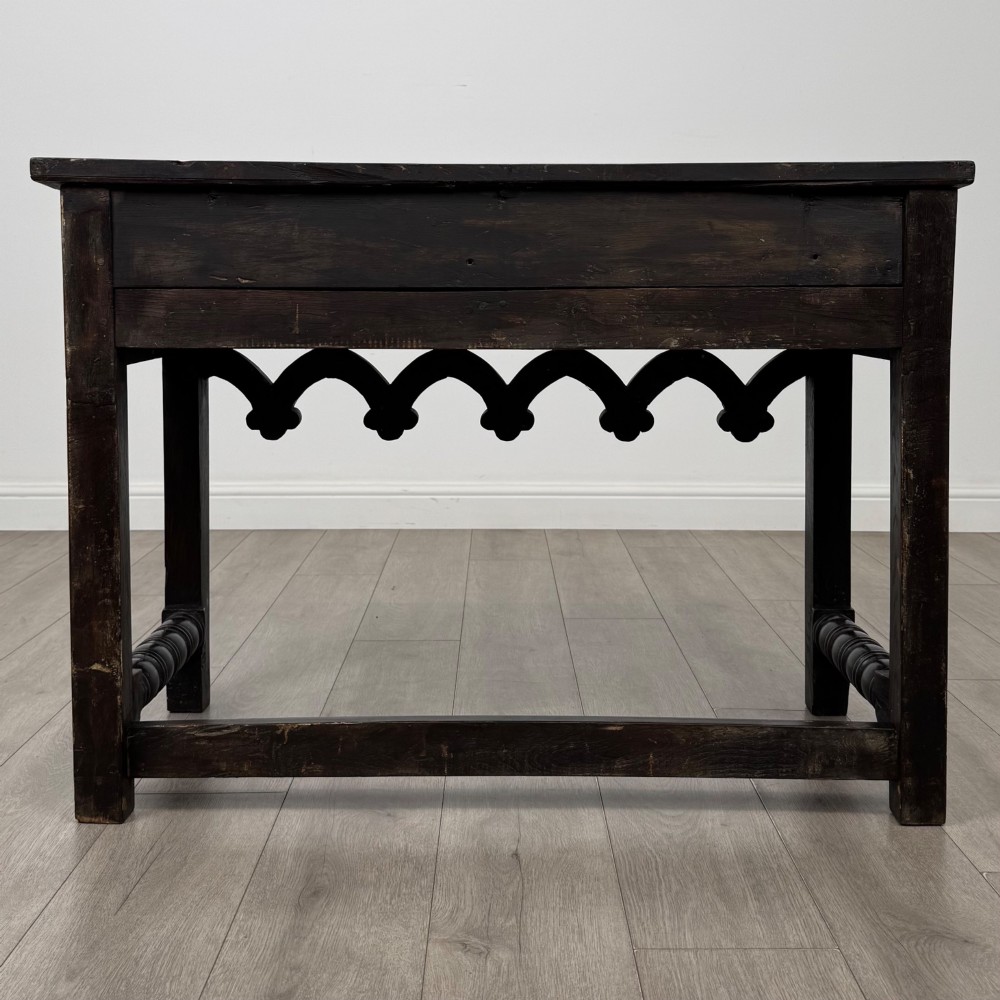 A dark oak 19th-century side table featuring floral relief carvings on two drawer fronts, a row of carved cusped arches along the lower apron, and turned side stretchers. View V