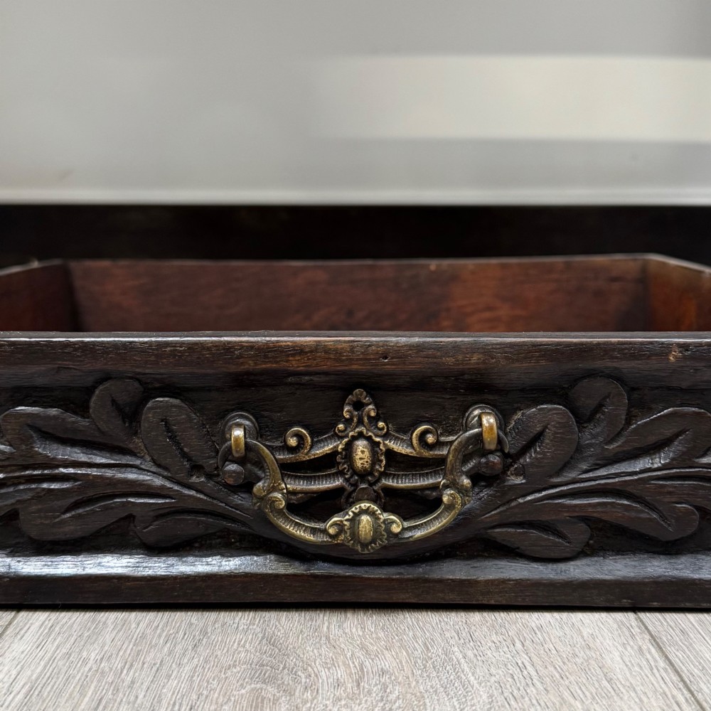 A dark oak 19th-century side table featuring floral relief carvings on two drawer fronts, a row of carved cusped arches along the lower apron, and turned side stretchers. View XI