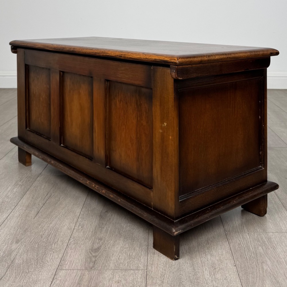 A rectangular dark oak blanket box featuring three carved front panels with Gothic arched details and a flat top lid. View VI