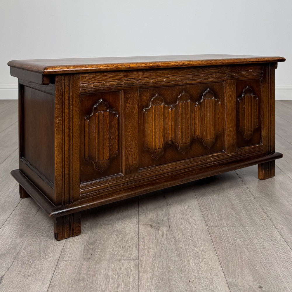 A rectangular dark oak blanket box featuring three carved front panels with Gothic arched details and a flat top lid. View VIII
