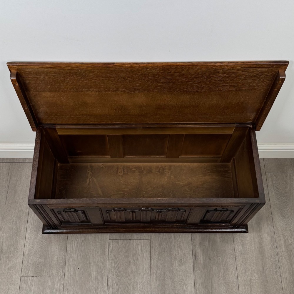 A rectangular dark oak blanket box featuring three carved front panels with Gothic arched details and a flat top lid. View X