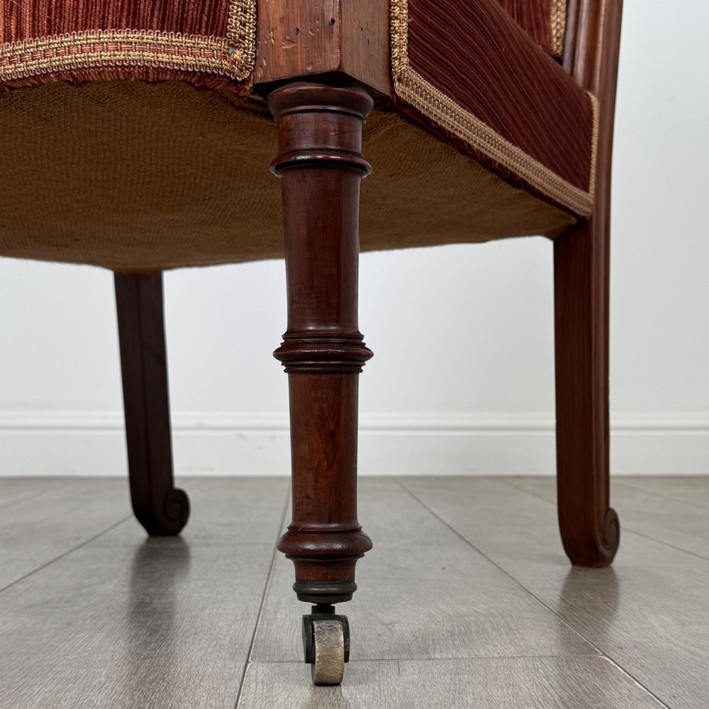 A Victorian rosewood armchair featuring a dark timber frame, carved scroll detailing, rust red velvet upholstery, and turned front legs on castors. View XII
