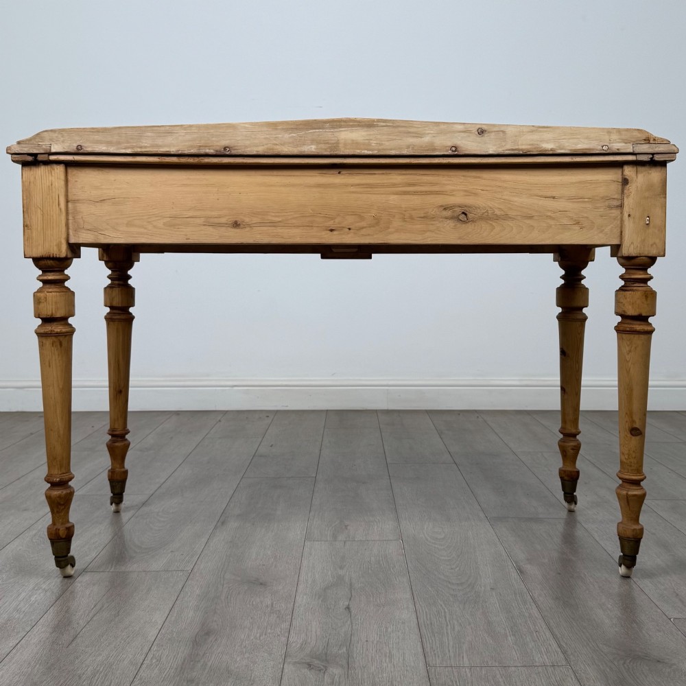 A 19th-century Victorian pine writing table featuring two drawers with brass handles, turned wooden legs, and ceramic castors. View V
