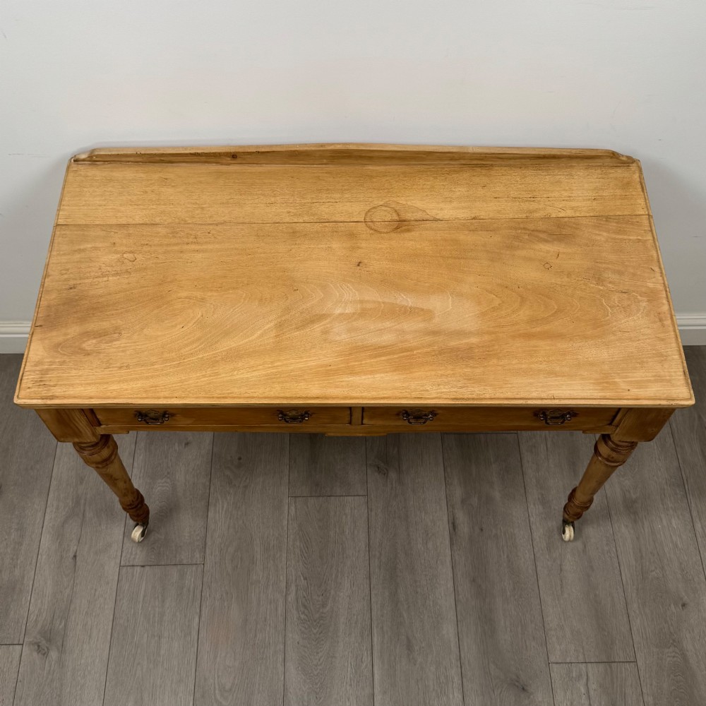 A 19th-century Victorian pine writing table featuring two drawers with brass handles, turned wooden legs, and ceramic castors. View IX