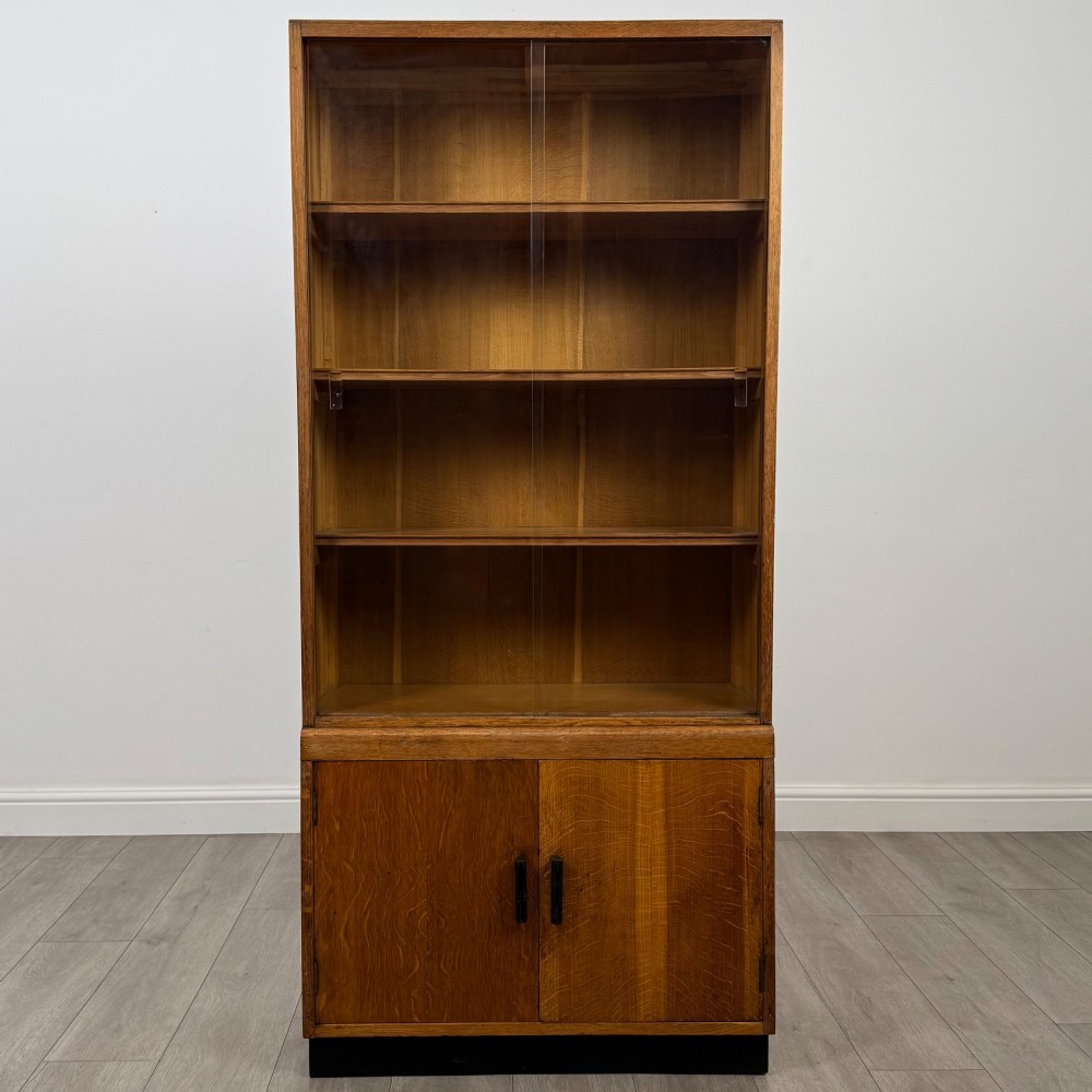 A tall vintage golden oak display cabinet featuring glazed sliding doors on top and a two-door cupboard base. View II