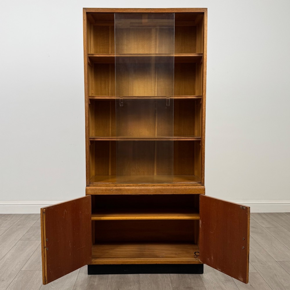 A tall vintage golden oak display cabinet featuring glazed sliding doors on top and a two-door cupboard base. View III