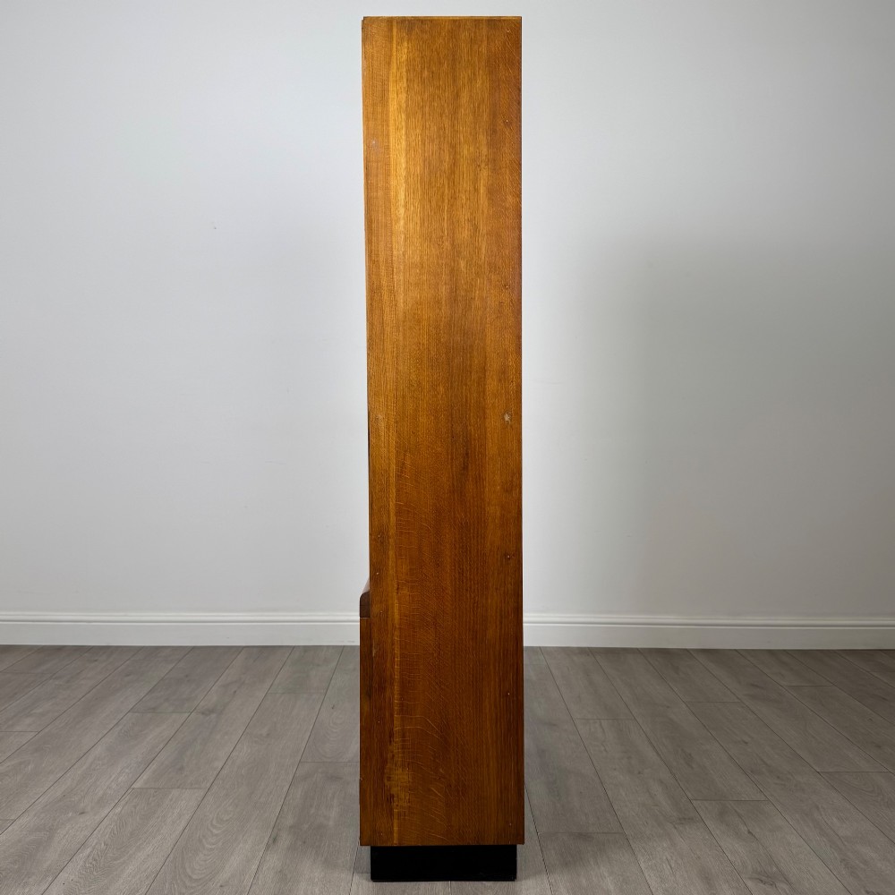 A tall vintage golden oak display cabinet featuring glazed sliding doors on top and a two-door cupboard base. View V