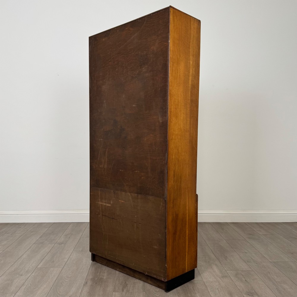 A tall vintage golden oak display cabinet featuring glazed sliding doors on top and a two-door cupboard base. View VIII