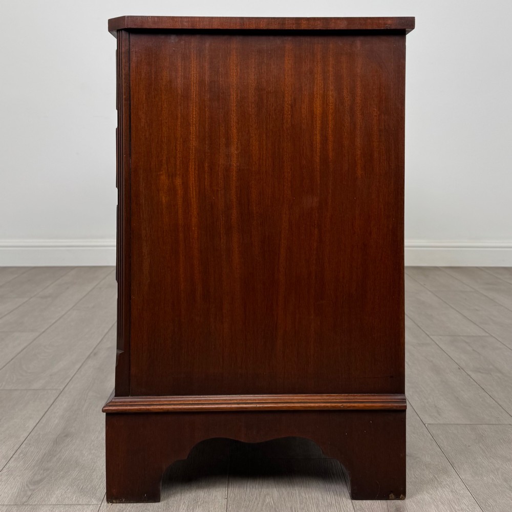 A wide 20th-century mahogany chest of drawers featuring multiple drawer tiers with flame mahogany veneer and decorative brass handles. View III