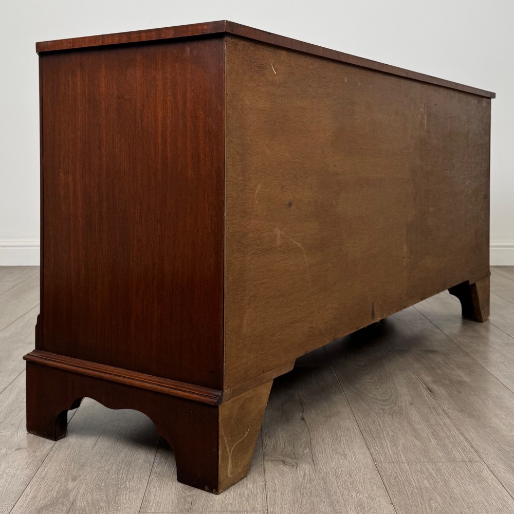 A wide 20th-century mahogany chest of drawers featuring multiple drawer tiers with flame mahogany veneer and decorative brass handles. View IV