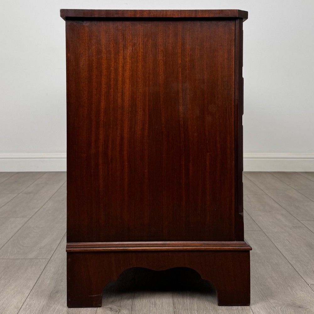 A wide 20th-century mahogany chest of drawers featuring multiple drawer tiers with flame mahogany veneer and decorative brass handles. View VII