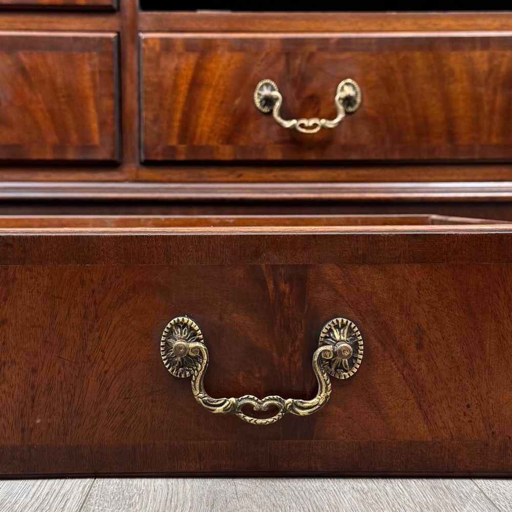 A wide 20th-century mahogany chest of drawers featuring multiple drawer tiers with flame mahogany veneer and decorative brass handles. View XI