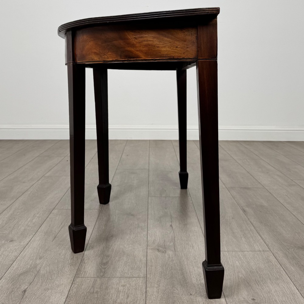 A nineteenth-century mahogany demi-lune side table featuring a semi-circular top, a veneered apron, and four square tapered legs ending in spade feet. View III
