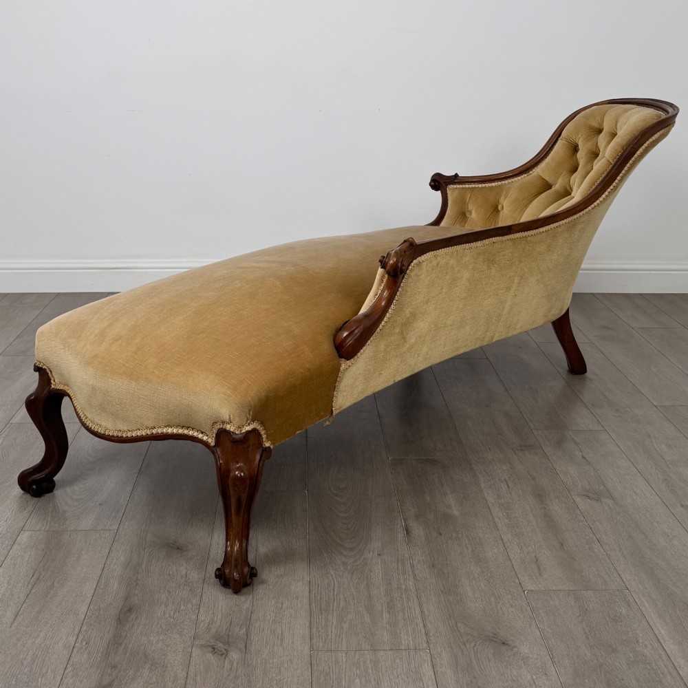 A Victorian mahogany chaise longue featuring ochre velvet button-backed upholstery, carved trim, and cabriole legs. View IV